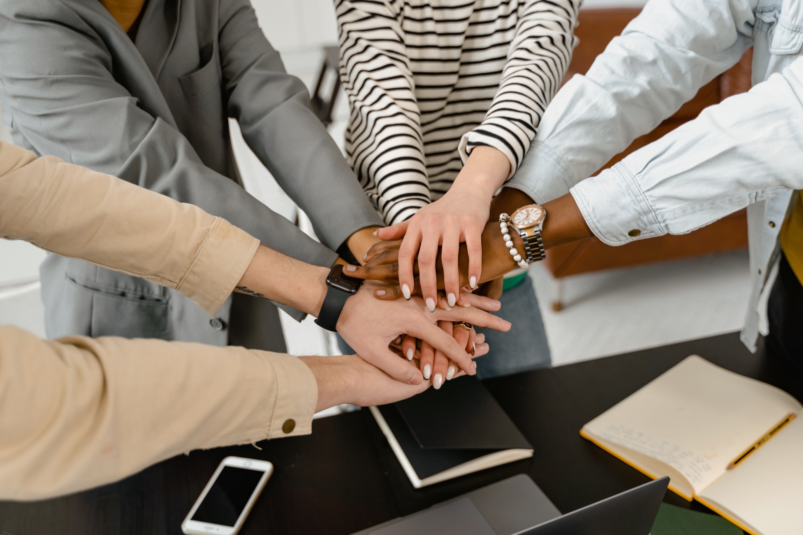 Coworkers stacking their hands together over a table